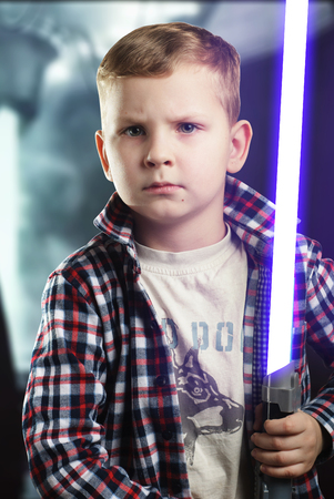 Little boy posing with a laser sword , a blue bright light, a young boy with a serious face, an aspiring actor,の写真素材
