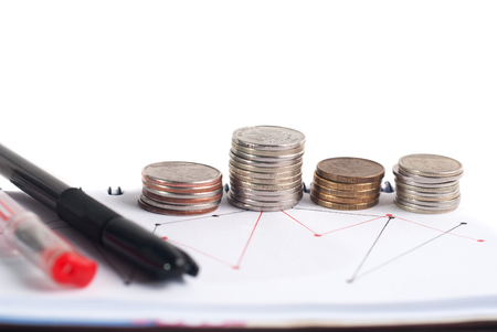 Closeup stack of coins, pen and notepad on white background. Business concept.の写真素材