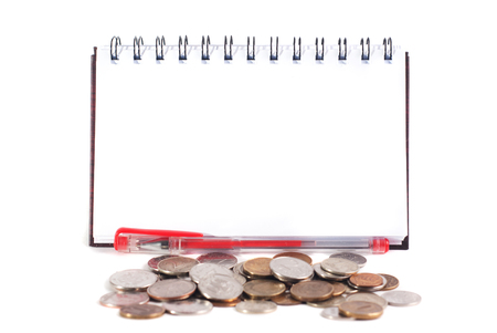 A notebook with a clean sheet, a red pen, lots of coins, financial conceptの写真素材