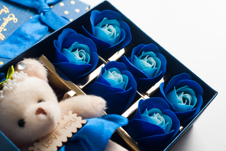The gift in the blue box with lid, isolated on a white background, a small Teddy bear, buds of blue rosesの写真素材