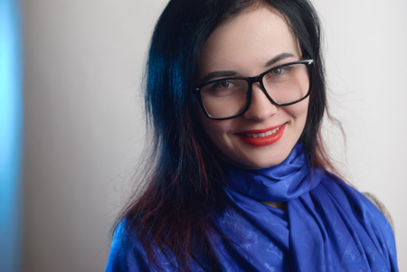 Girl with glasses on a white background, hipster glasses, cute brunette, austere clothing, a woman in a blue shawlの写真素材
