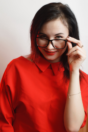 Closeup portrait of female model in red dress on white background, cute brunette with black glasses,の写真素材