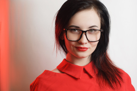 Closeup portrait of female model in red dress on white background, cute brunette with black glasses,の写真素材
