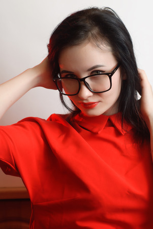 Closeup portrait of female model in red dress on white background, cute brunette with black glasses,の写真素材