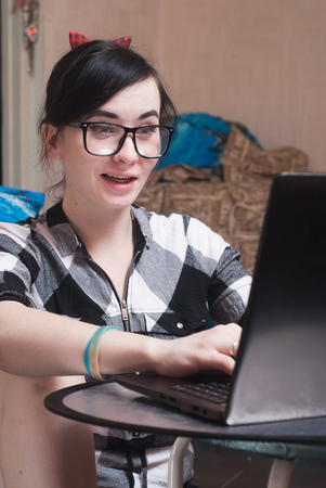 Cute girl working on laptop at home, brunette in black glassesの写真素材