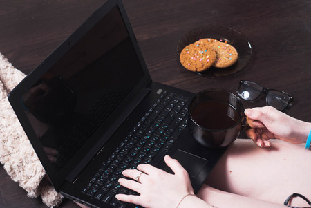 A female blogger. girl drinking coffee in front of laptop, sitting on the floor, body partsの写真素材