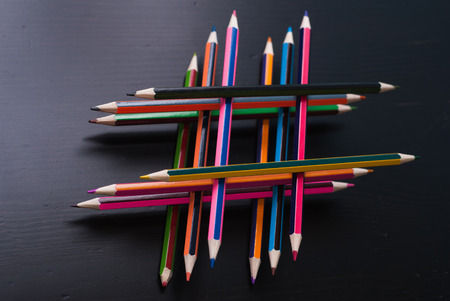 Hashtag of pencils. stacked colored pencils on the black table dark wooden surface, cost of pencilsの写真素材