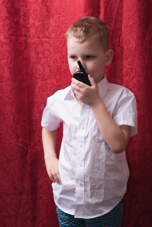 Boy with a walkie-talkie, a child in a white shirt, red background,の写真素材