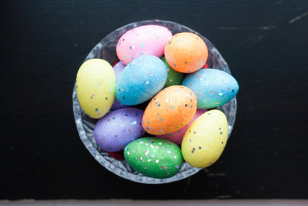 Easter eggs in crystal dishes on a black wooden background, colored decorative eggs, happy Easter