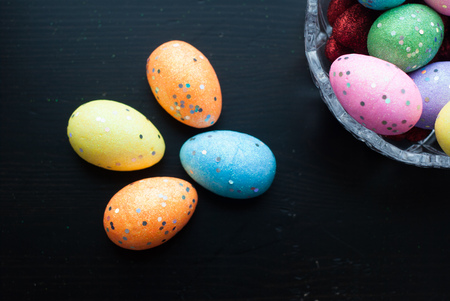 Easter eggs in crystal dishes on a black wooden background, colored decorative eggs, happy Easterの写真素材