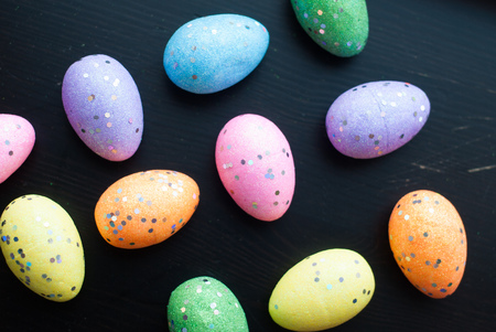 Colored eggs on black background, top view, decorative ornaments for Easter, pattern eggsの写真素材