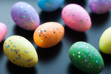 Colored eggs on black background, top view, decorative ornaments for Easter, pattern eggsの写真素材