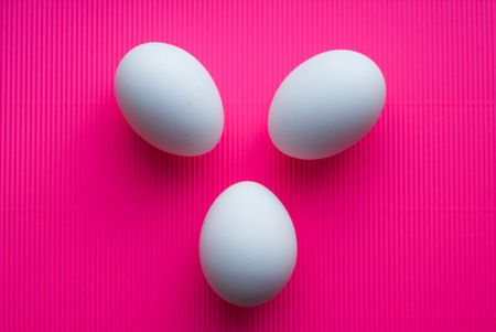 Easter eggs on pink background, happy Easter, white chicken eggs, checkered backgroundの写真素材