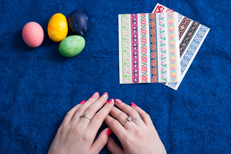 Easter eggs on a blue towel, female hands with beautiful manicure. decorative stickerの写真素材