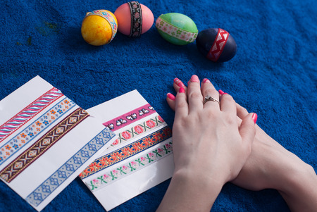 Easter eggs on a blue towel, female hands with beautiful manicure. decorative stickerの写真素材