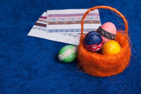 Easter eggs in an orange basket on blue background, happy Easter, decorative stickers, festiveの写真素材