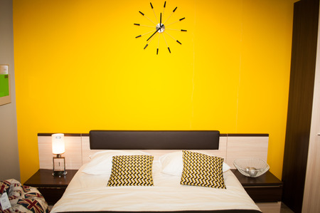 Empty bed with pillows on a background of yellow wall, bedroom interior,の写真素材