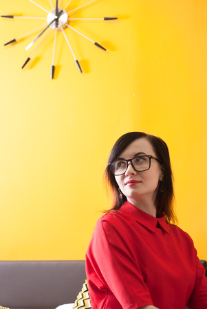 Girl in a red dress on a yellow background, cute brunette in hipster glassesの写真素材