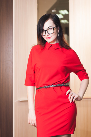 Portrait of beautiful and young female model in red dress and elegant spectacles posing .Beauty, fashion, optics.の写真素材