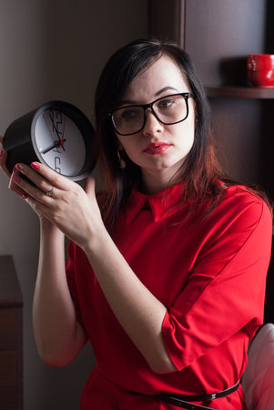 Business woman holding a clock, a portrait of a woman in a red dress, a photo in a dark way,...