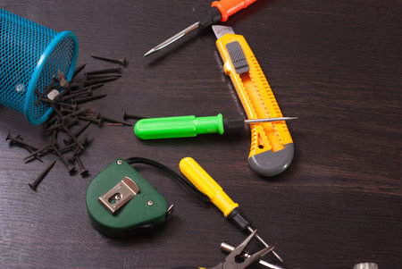 Building tools on wooden background, repair kit, bright screwdrivers, hammer, utility knife, tape...