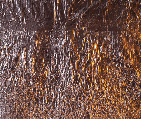 Abstract background, crumpled foil, textured surface, yellow patches on the surfaceの写真素材
