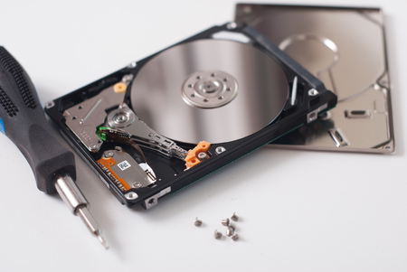 Took apart the hard drive from the computer, HDD drive, mirror effect, screwdriver with rubber handle, unscrewed the screws on a light backgroundの写真素材