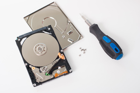 Took apart the hard drive from the computer, HDD drive, mirror effect, screwdriver with rubber handle, unscrewed the screws on a light backgroundの写真素材