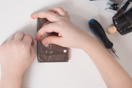 Hands of a little boy with the screwdriver, disassembling the hard disk drive, boy busyの写真素材