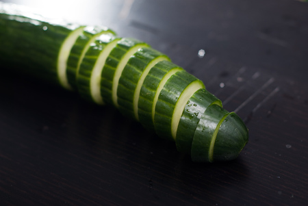 Green cucumber, sliced on a black Board, fresh vegetables, healthy eating conceptの写真素材