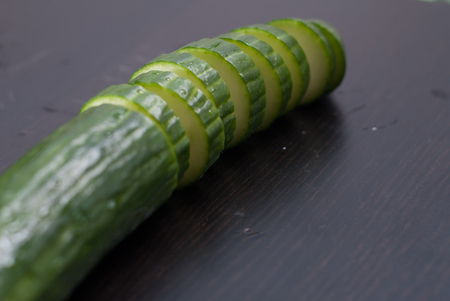 Green cucumber, sliced on a black Board, fresh vegetables, healthy eating conceptの写真素材