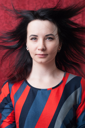 Pretty woman with hair in the wind, a designer dress in the style of futurism, red background,の写真素材