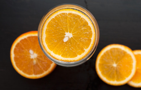 Orange slice in the glass, the view from the top, on a black wooden background, closeup, composition of sliced orangesの写真素材