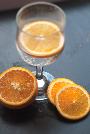 Orange slice in the glass, the view from the top, on a black wooden background, closeup, composition of sliced orangesの写真素材