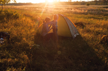 Camping, mother and son in the tent at sunset, green grass, active lifestyleの写真素材