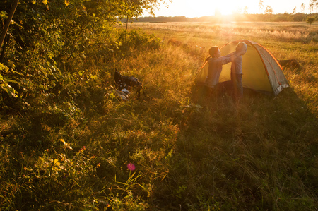 Camping, mother and son in the tent at sunset, green grass, active lifestyleの写真素材