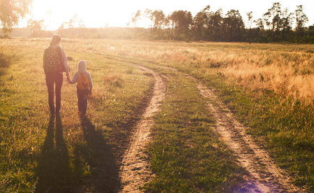 mother and son walking on the meadow at sunset, country road, day motherの写真素材