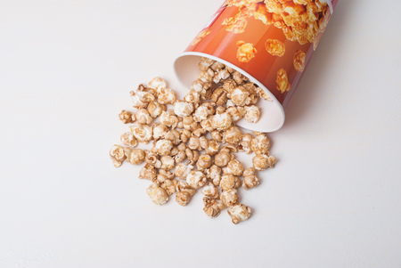Popcor poured from a cardboard Cup on white backgroundの写真素材