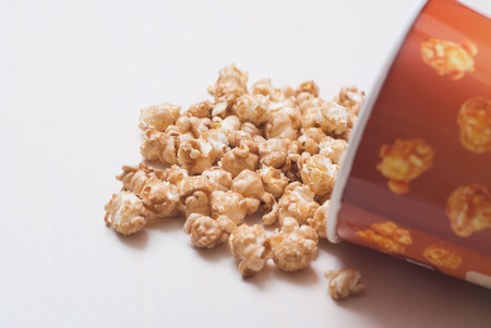 Popcor poured from a cardboard Cup on white backgroundの写真素材