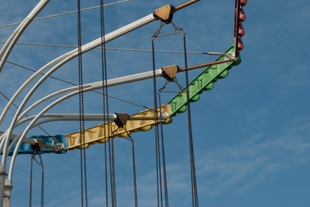 The old carousel on the background of blue sky, the detail of the circular swing, long chainの写真素材