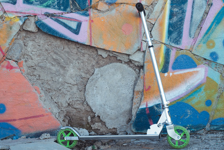 Kick Scooter on the background of old stone walls painted with colorful graffitiの写真素材