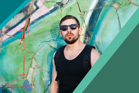 Portrait of a young man with a beard and sunglasses against graffiti background outdoors, sunset, emotive portrait, designer corners,の写真素材