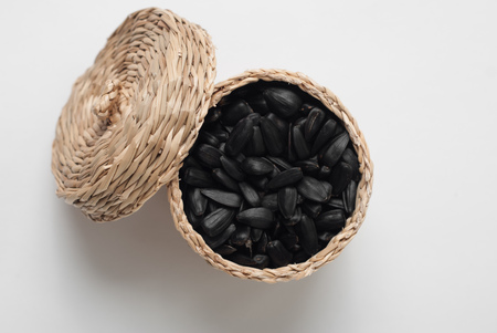sunflower seeds in a wicker basket with lid on white background, fried sunflower seedsの写真素材