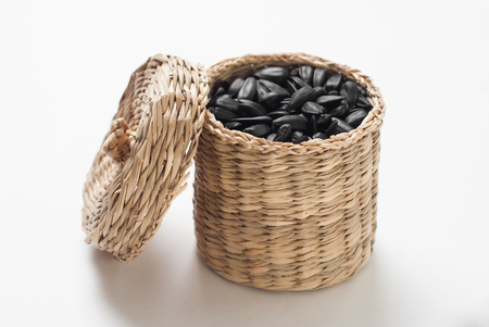 sunflower seeds in a wicker basket with lid on white background, fried sunflower seedsの写真素材