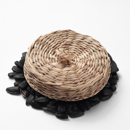 Dry sunflower seeds under straw braided cap, on a white backgroundの写真素材