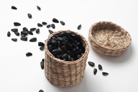 sunflower seeds in a wicker basket with lid on white background, fried sunflower seedsの写真素材