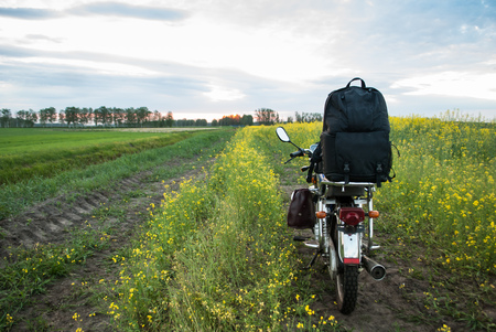 Adventure on a motorcycle. Path along the rapeseed field at sunset. Active guests.の写真素材