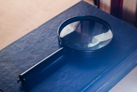 Magnifier with black handle is on the cover of the book, glare and reflections on the magnifying glassの写真素材