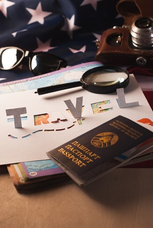 The concept of travel, passport, glasses, magnifying glass,stencil, paper, map of the world on the American flagの写真素材