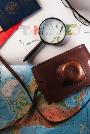 The concept of travel, passport, glasses, magnifying glass,stencil, paper, map of the world on the American flagの写真素材